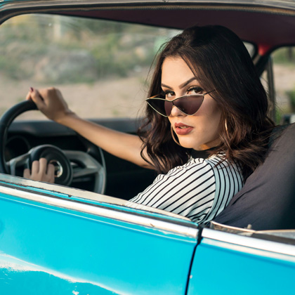 A woman in the driver's seat of a classic car