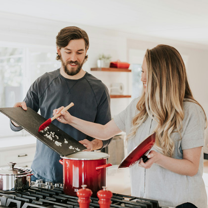 A man and woman cooking at the stove in a kitchen