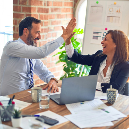 A businessman and businesswoman celebrating in a business setting