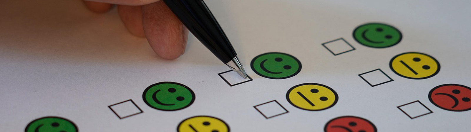 A person holding an ink pen filling out a customer satisfaction survey