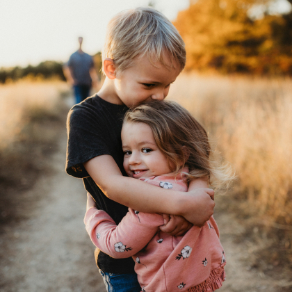 Young brother and sister hugging in a rural area